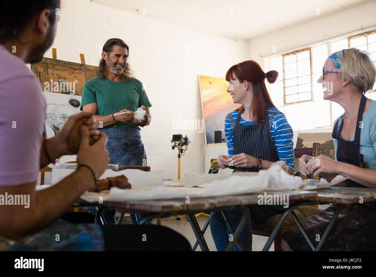 Smiling adult student looking at teacher explaining while standing in art class Stock Photo