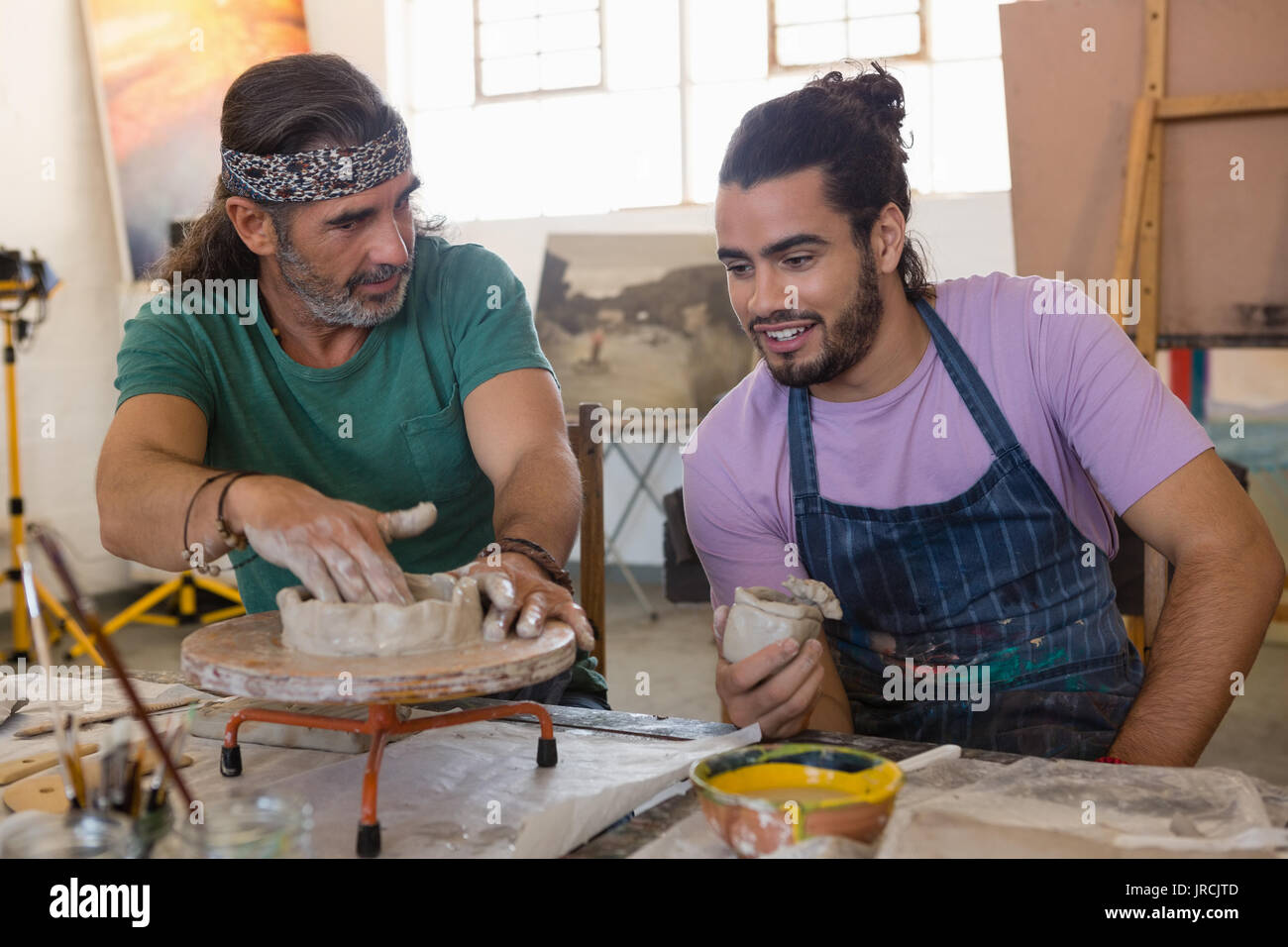 Man looking at teacher explaining to make clay structure pottery wheel in art class Stock Photo