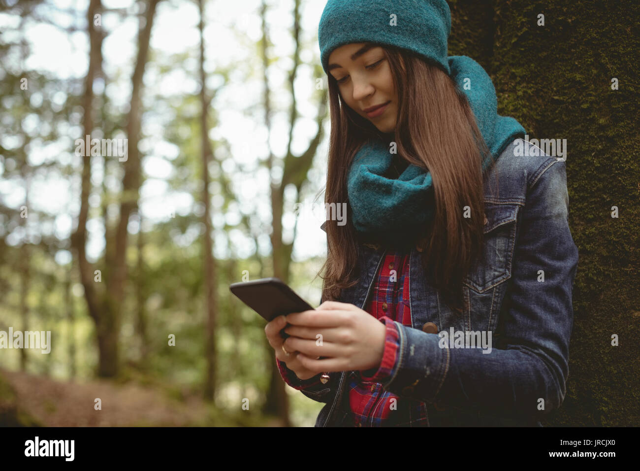 Smiling woman using digital tablet in forest Stock Photo