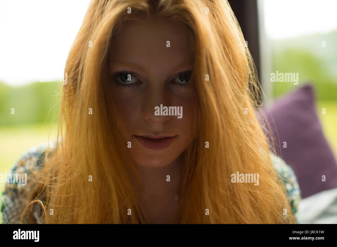 Close up portrait of young woman with redhead sitting at home Stock Photo