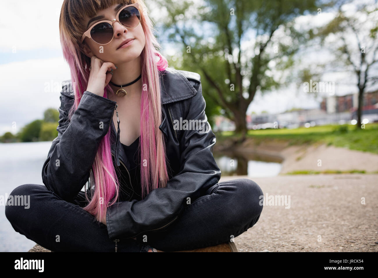 Beautiful woman sitting at riverbank in park Stock Photo - Alamy