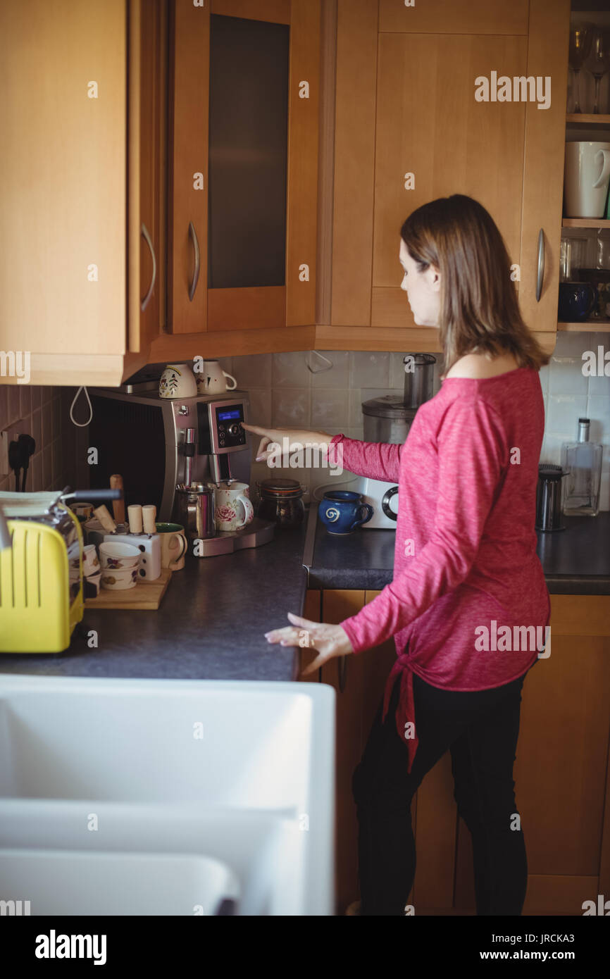 Woman using coffeemaker in kitchen at home Stock Photo