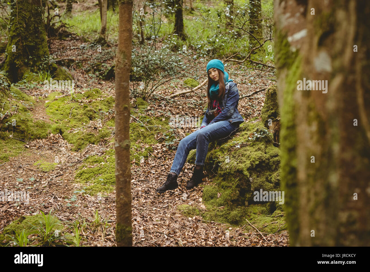 Portrait of woman sitting on rocks in forest Stock Photo