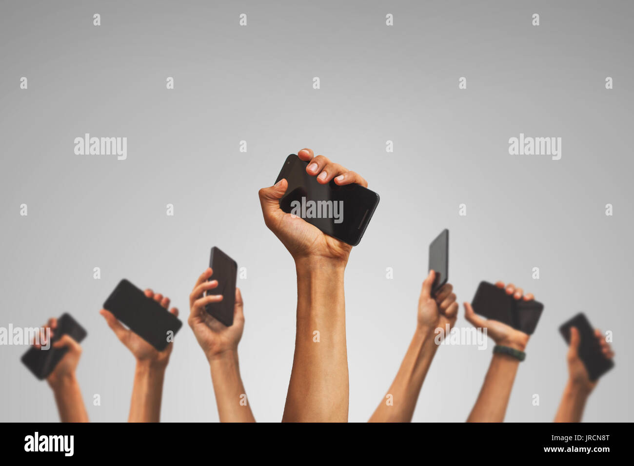 group of people's hands holding phones and rising them up against sky Stock Photo