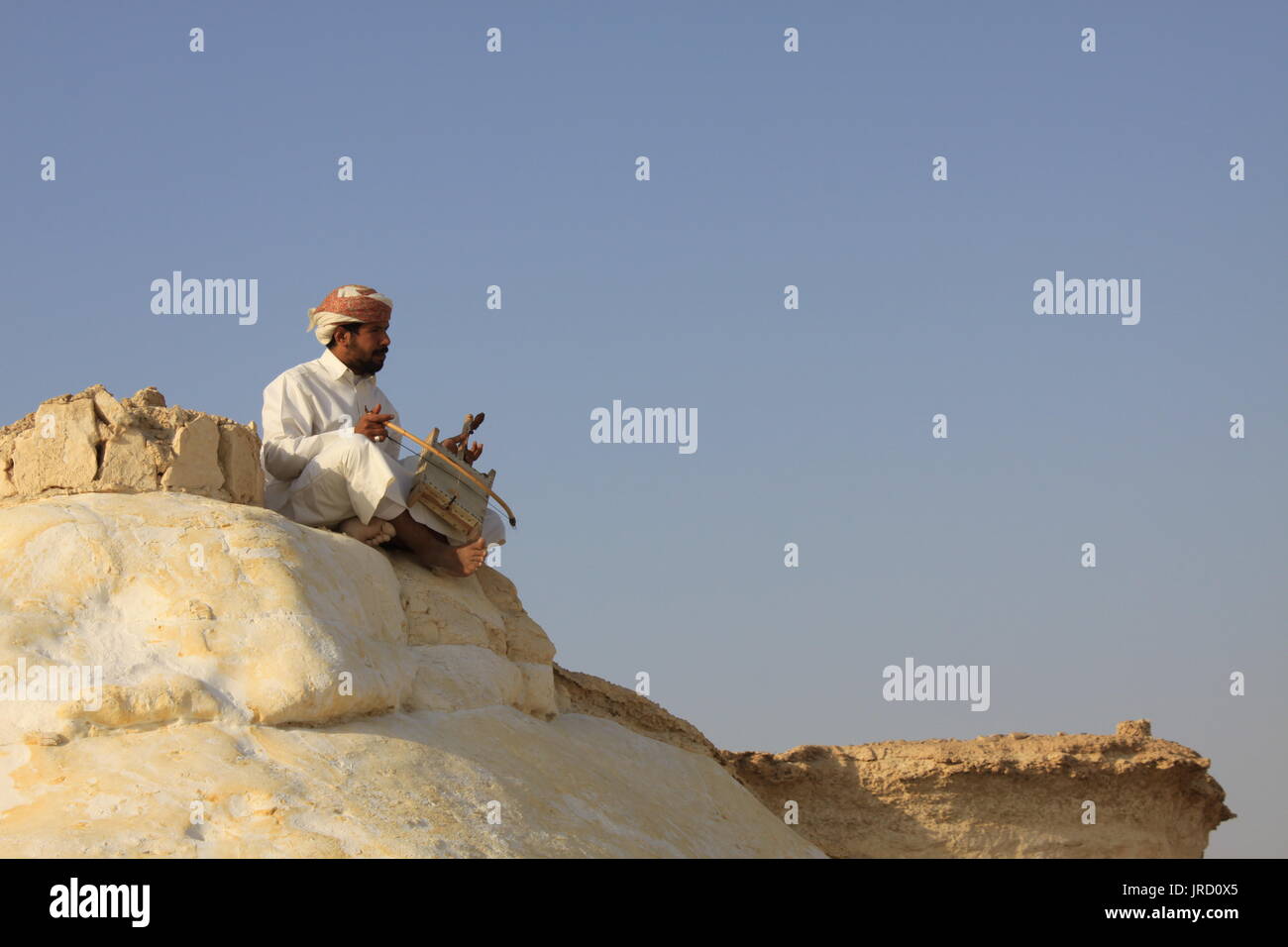 Man on a cliff playing traditional Arabic music by using classical instrument Stock Photo