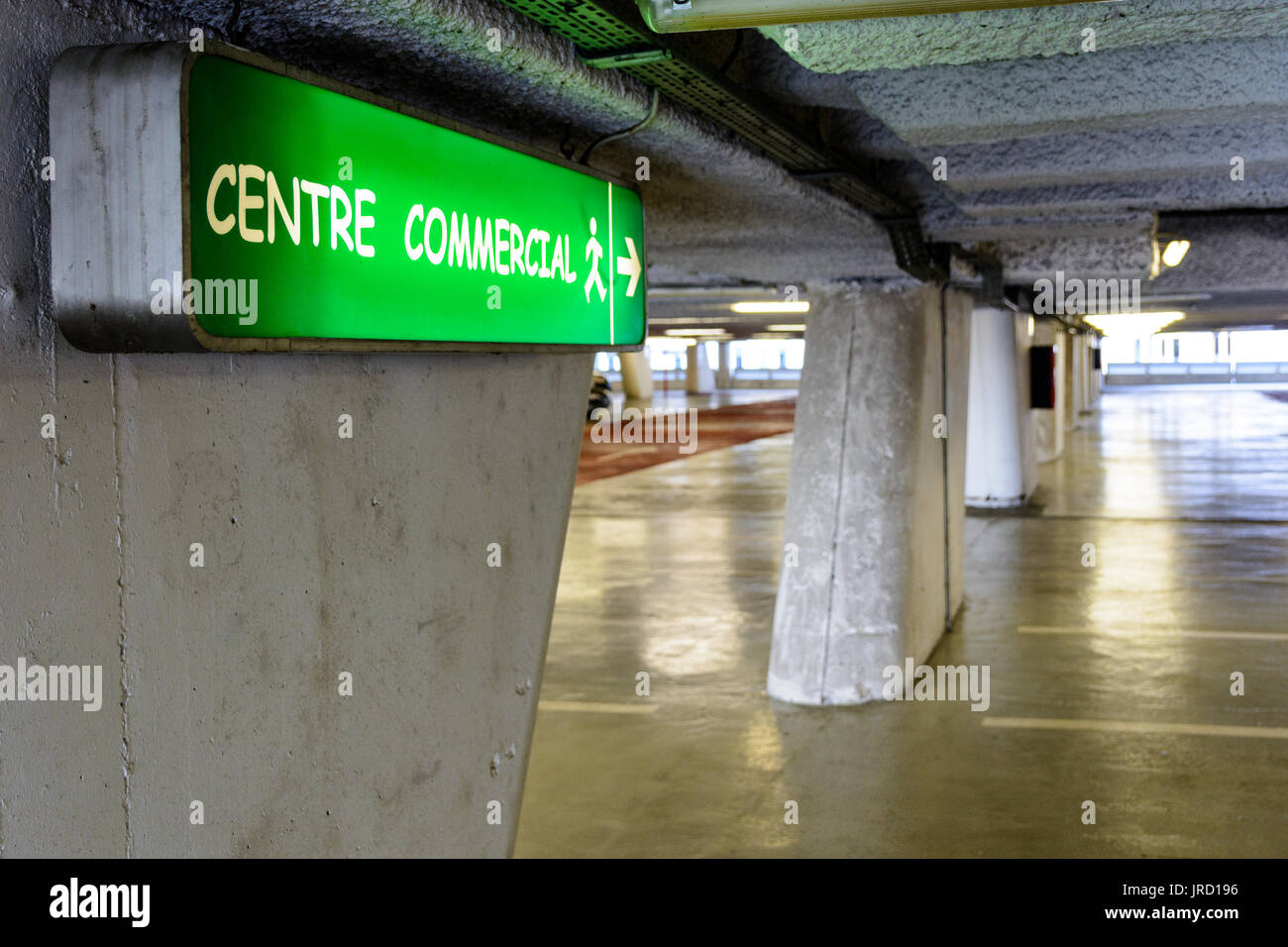 Luminous signs indicating the direction to the commercial center in an old decrepit underground parking lot. Stock Photo