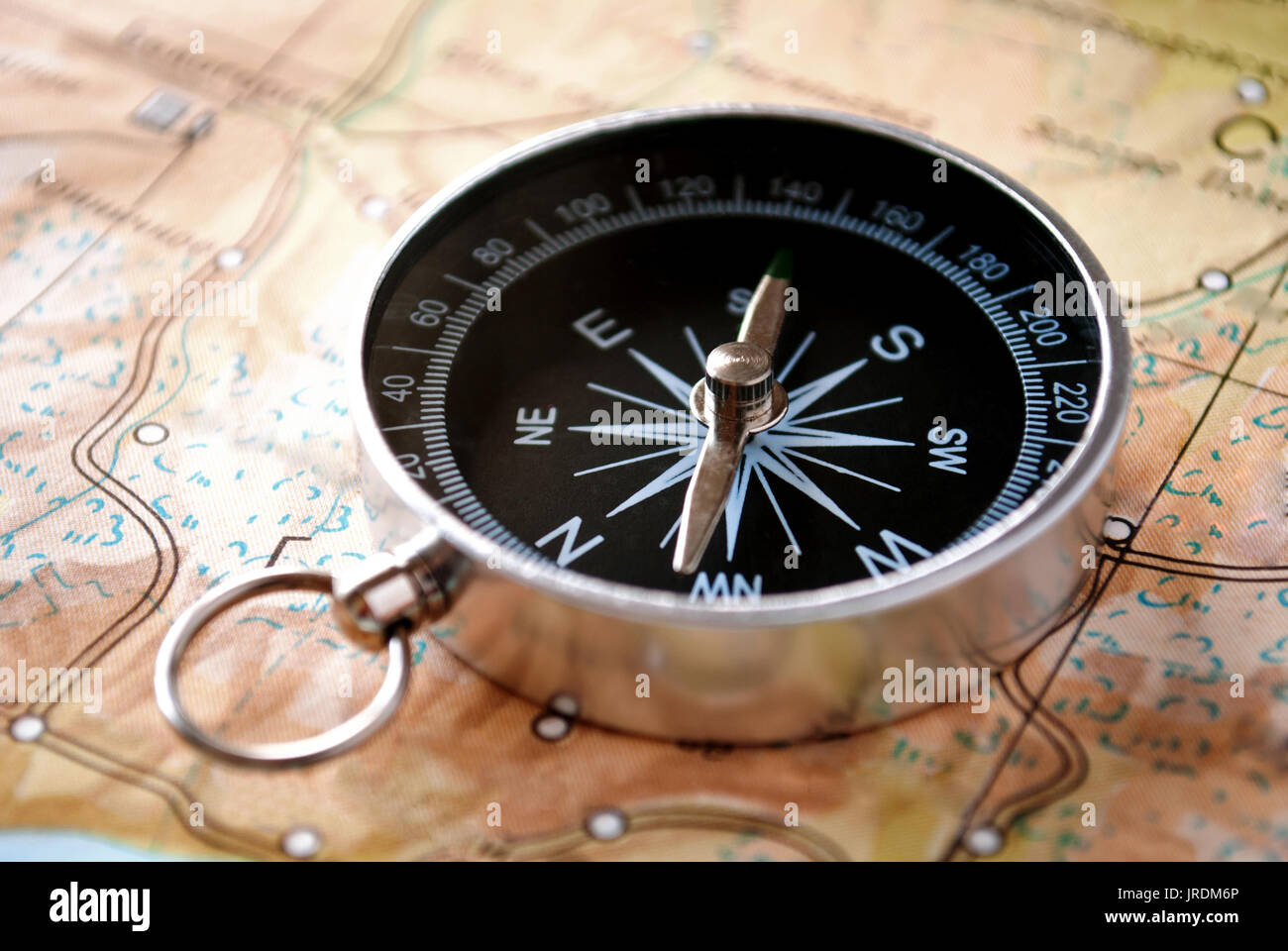 Handheld compass lying on a map showing the needle and cardinal points