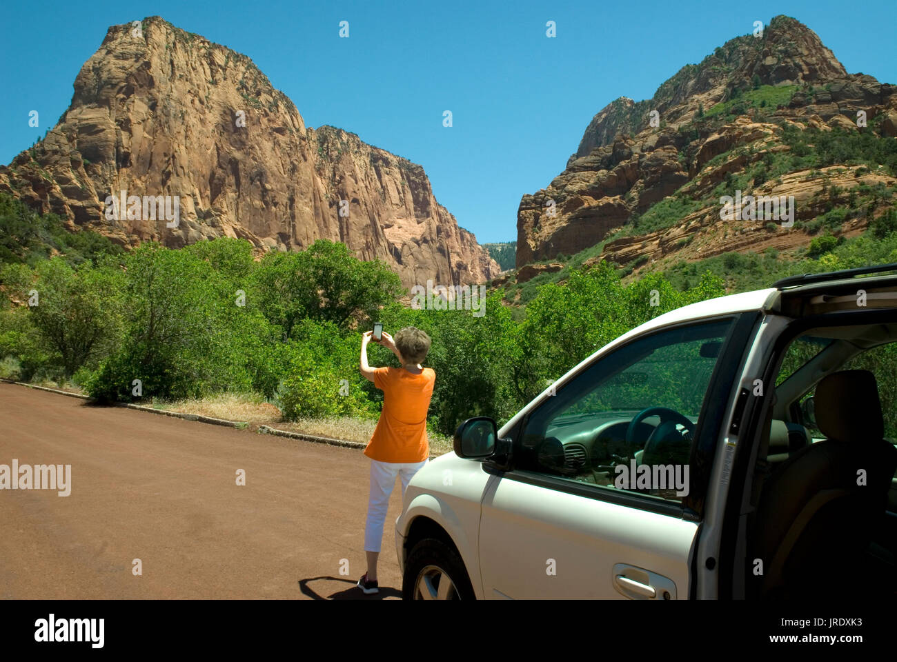 Caucasian Senior Female wearing orange shirt (age 60-70) taking photo with cellphone at  Zion National Park Springdale Utah USA. Stock Photo