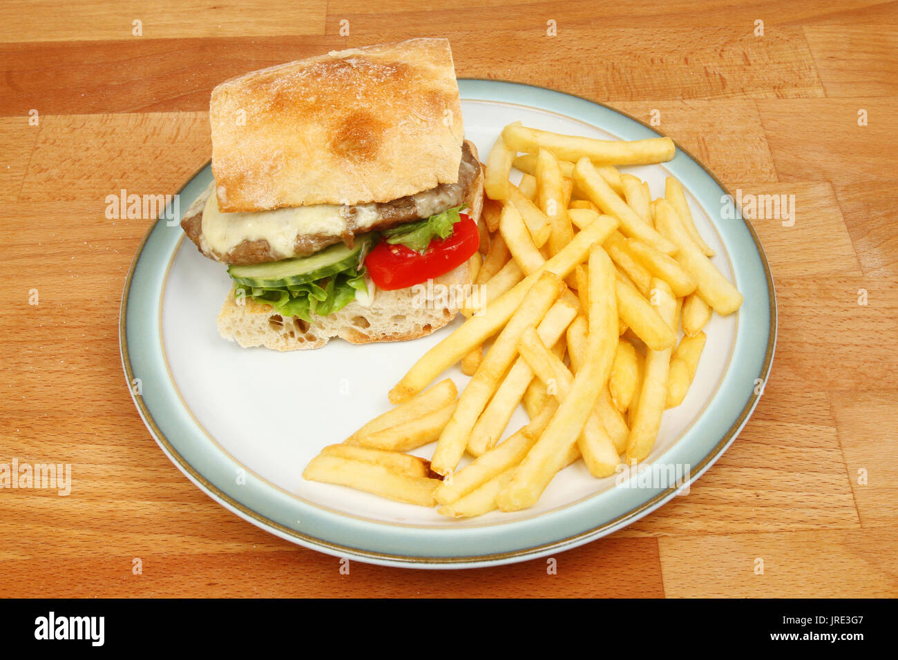 Cheeseburger with French fries on a plate on a wooden tabletop Stock Photo