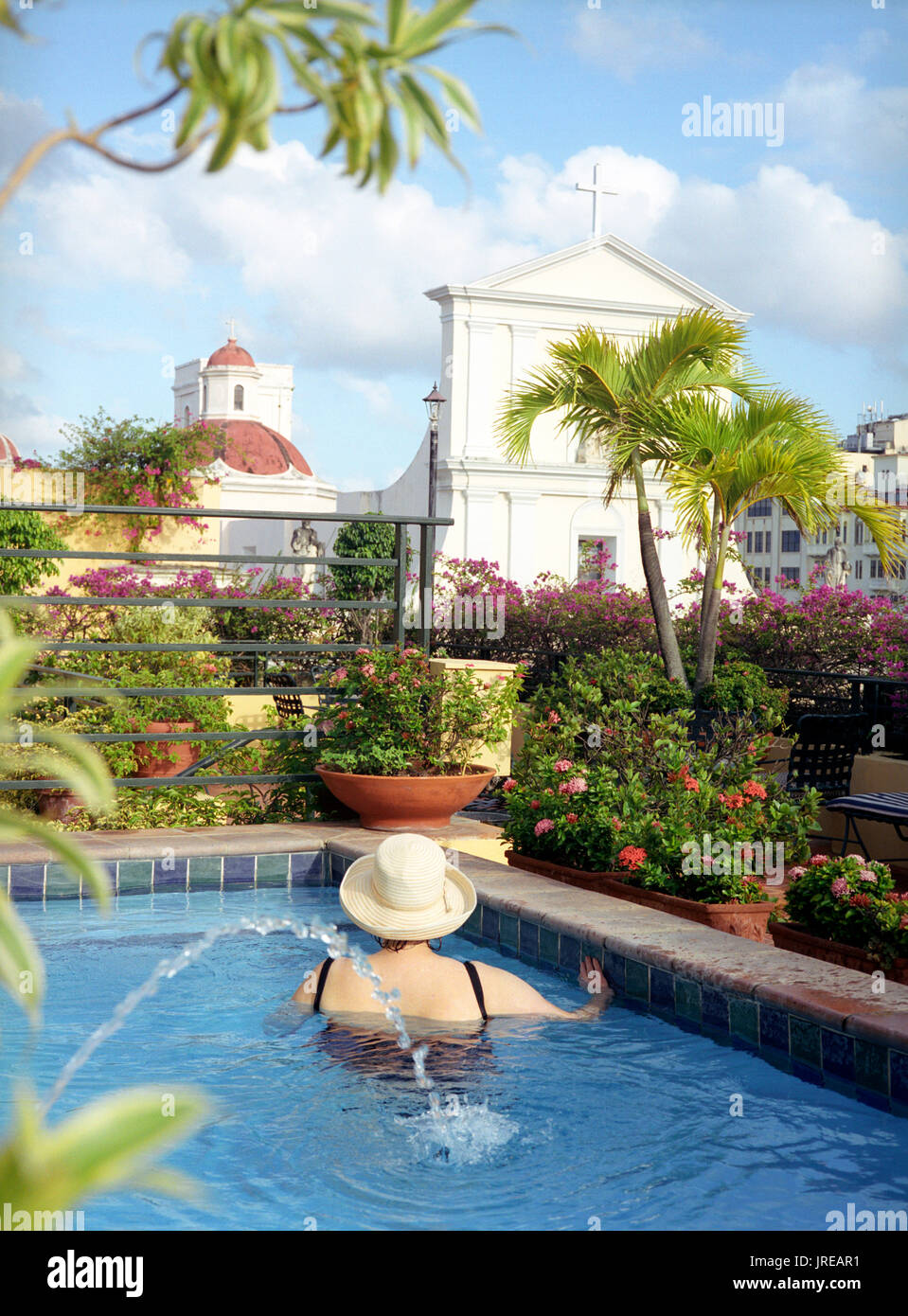 A women looks out at the Catedral de San Juan from the pool at the El Convento hotel.  An architectural landmark in the heart of historic Old San Juan Stock Photo