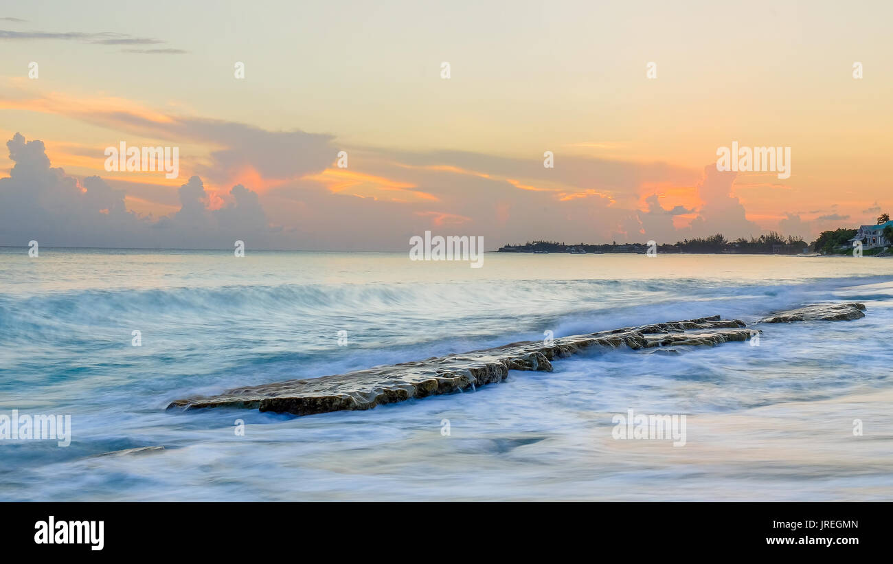 Sunset over a flat rock formation in the Caribbean Sea at Cemetery Beach, Grand Cayman, Cayman Islands Stock Photo