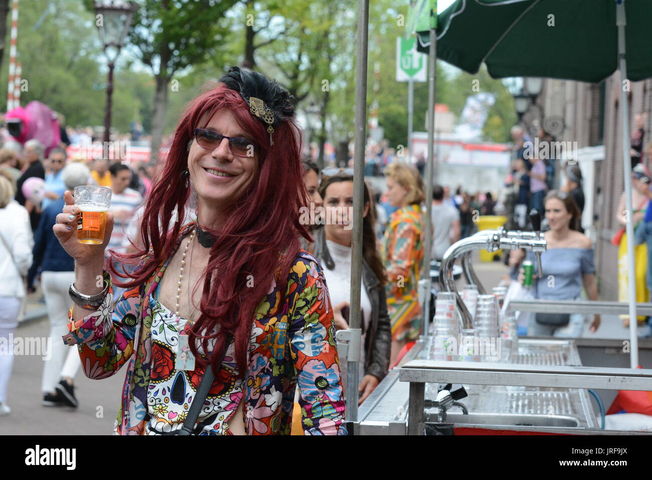 A reveller in drag drinks a toast to celebrate Amsterdam gay prIde. Credit: Patricia Phillips/Alamy live news Stock Photo