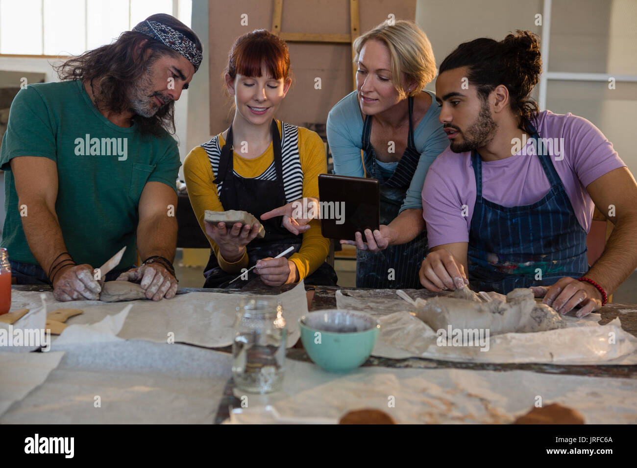Teacher holding digital tablet while guiding students in art class Stock Photo