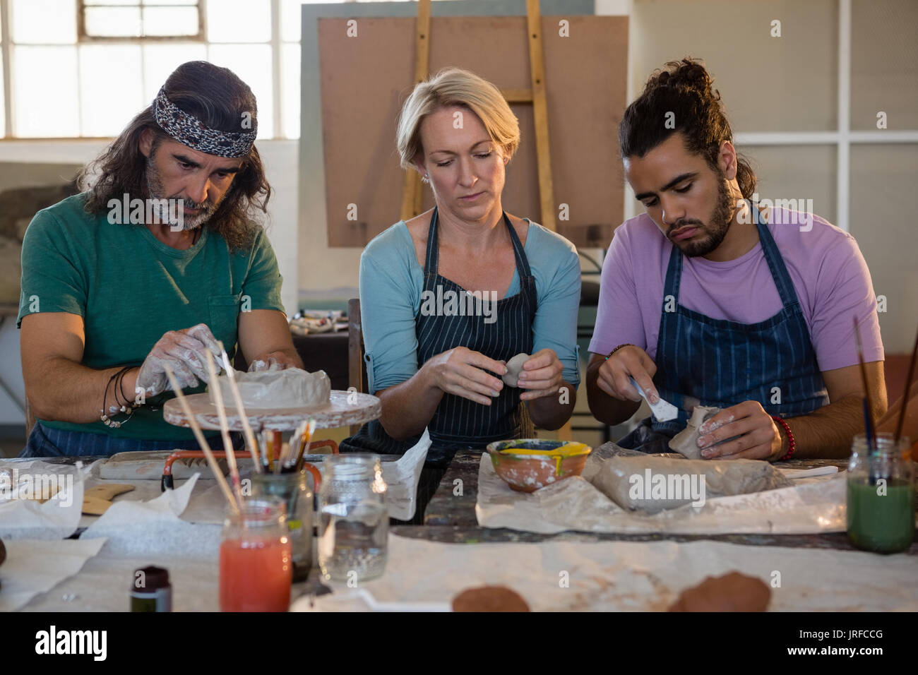 Teacher with students making clay products while sitting in art class Stock Photo