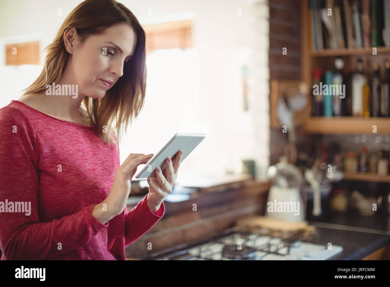 Woman using digital tablet in kitchen at home Stock Photo