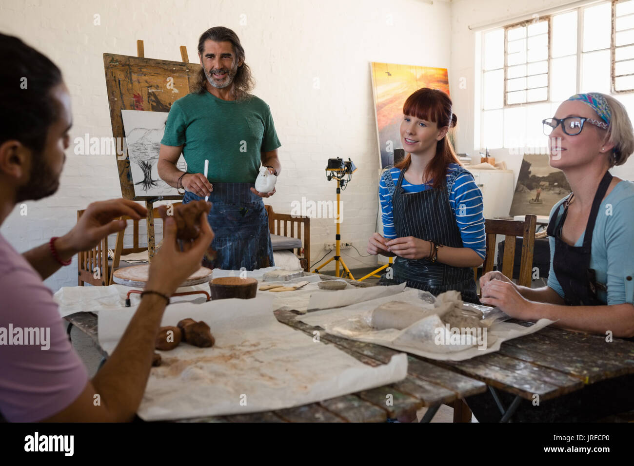 Teacher and student looking man making sculpture while practicing in art class Stock Photo