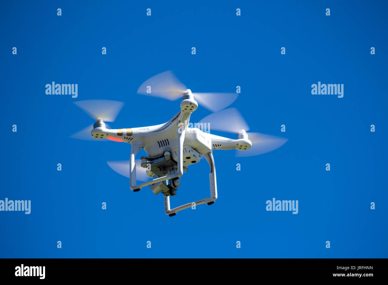 Drone or unmanned aerial vehicle in flight against blue sky Stock Photo
