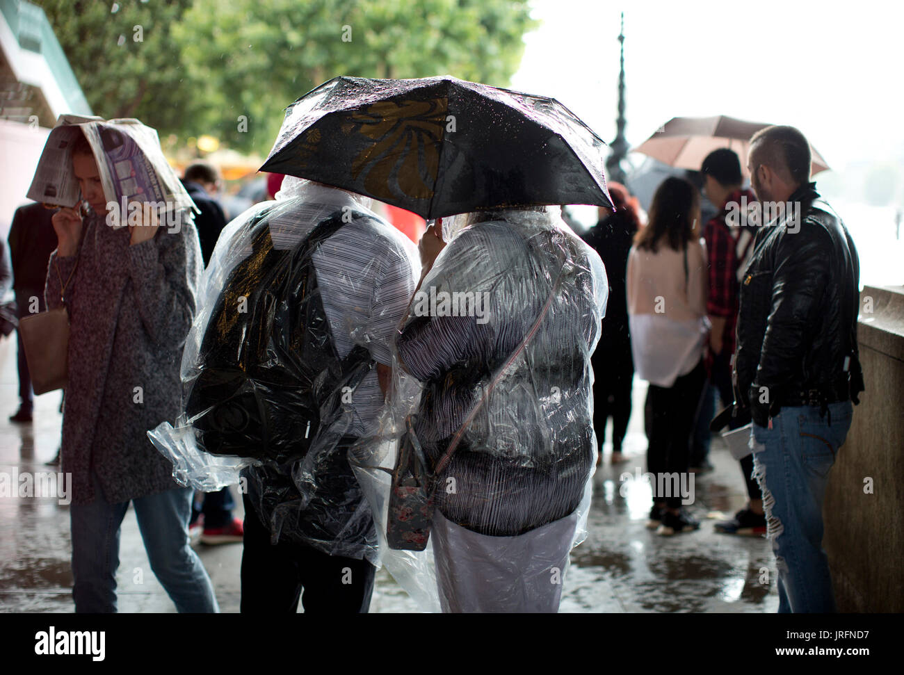 People shelter under umbrellas from a downpour at the Southbank, London