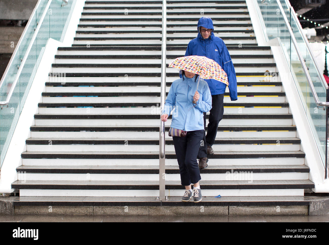 People shelter under umbrellas from a downpour at the Southbank, London