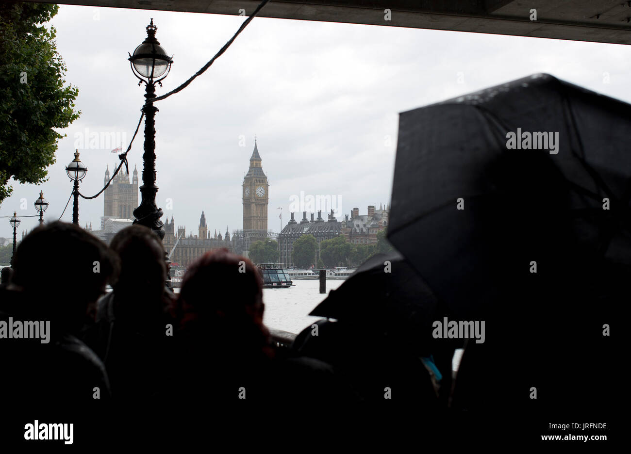 People shelter under umbrellas from a downpour at the Southbank, London