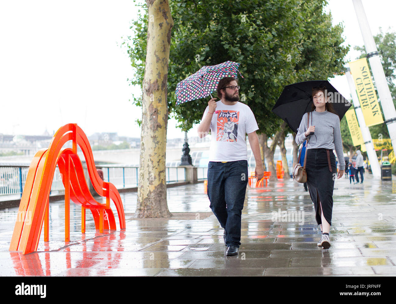 People shelter under umbrellas from a downpour at the Southbank, London