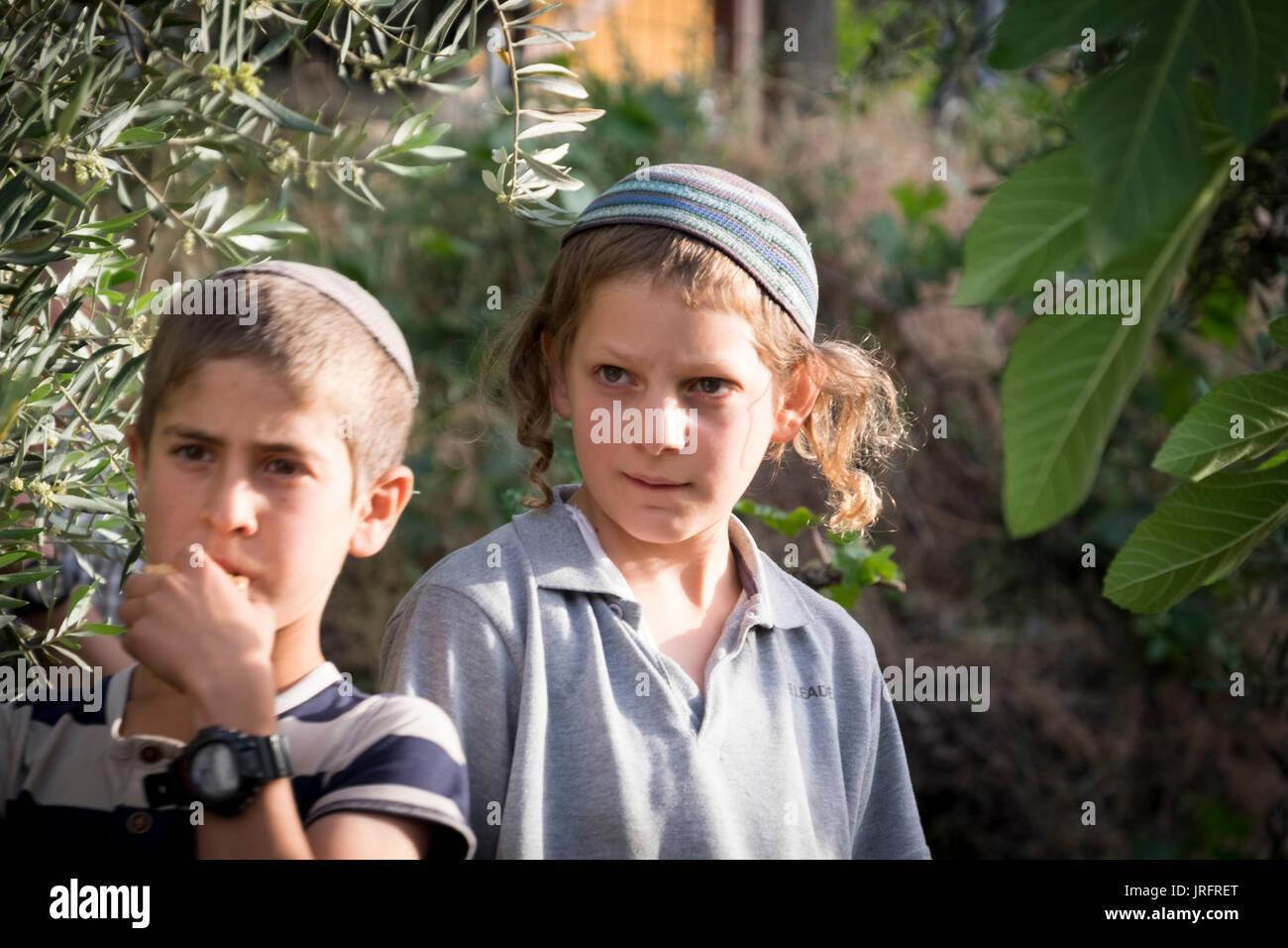 Two Israeli settler children are transfixed by an argument between a settler and a Palestinian in the Occupied Territories of the West Bank in Hebron Stock Photo