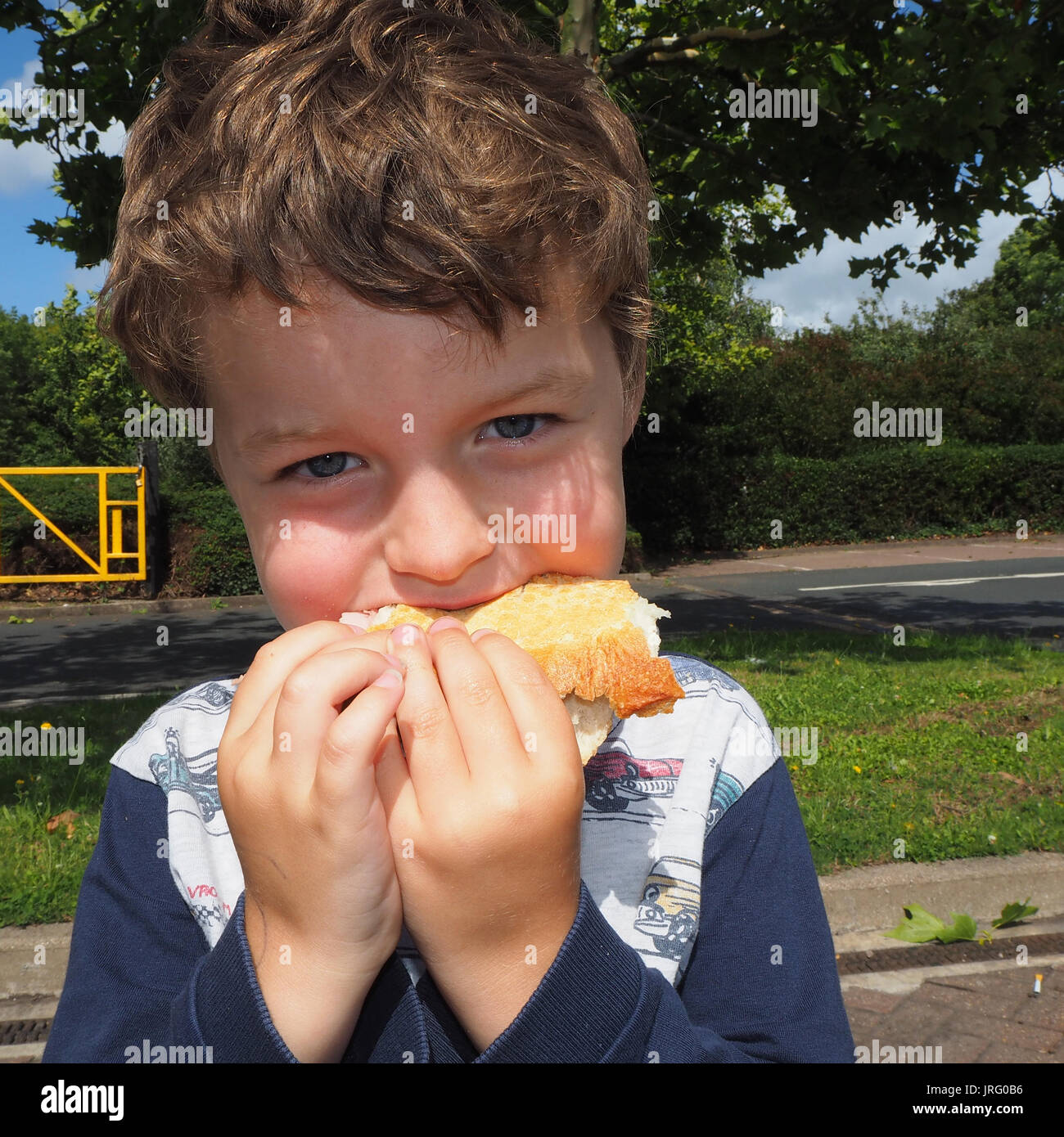 Young boy eating ham baguette Stock Photo - Alamy