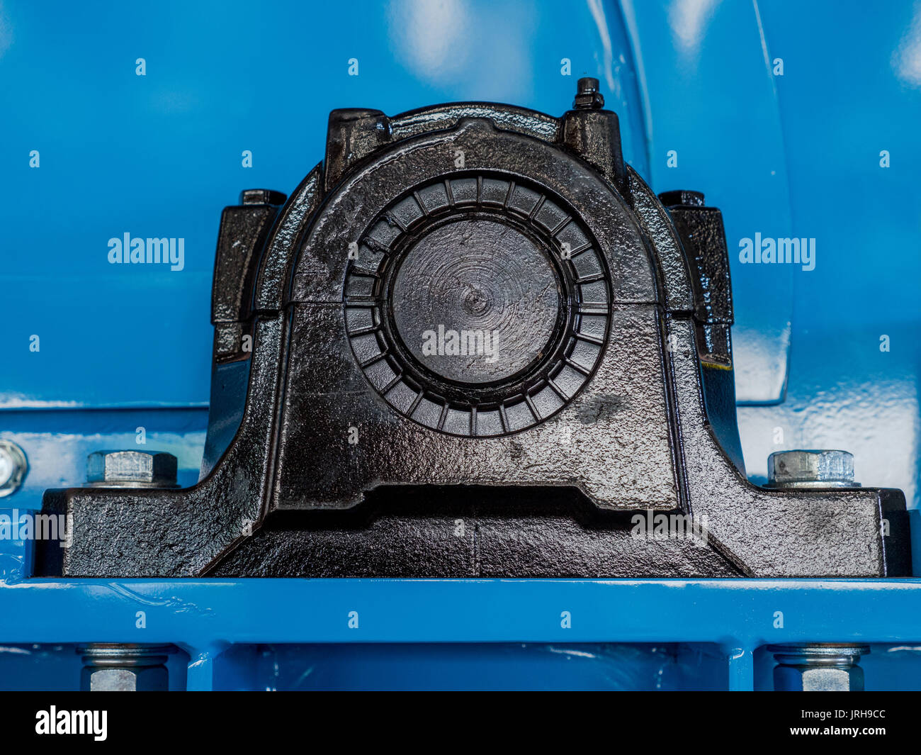 Black ball bearing housing on a blue machine. End of drive shaft