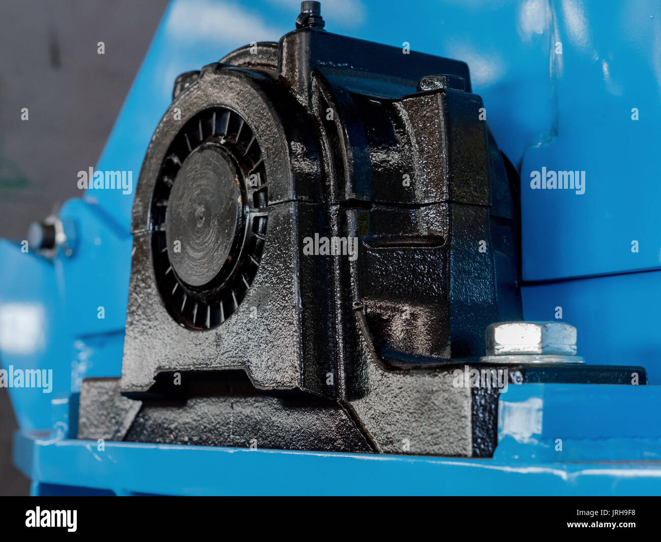 Black ball bearing housing on a blue machine. End of drive shaft