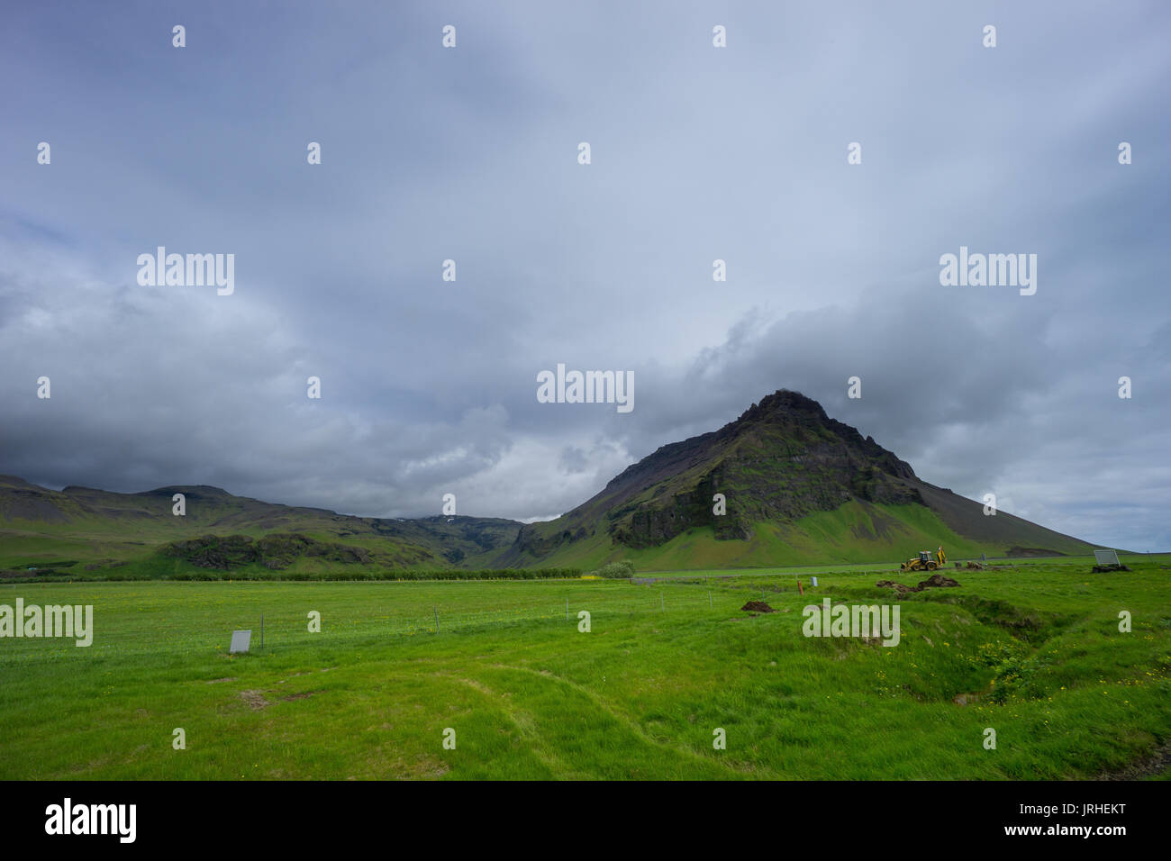 Iceland - Green meadow with dredger and mountain Stock Photo