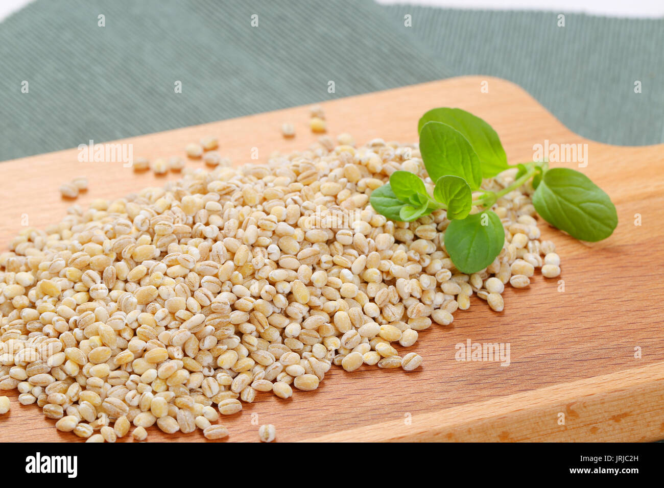 pile of pearl barley on wooden cutting board - close up Stock Photo