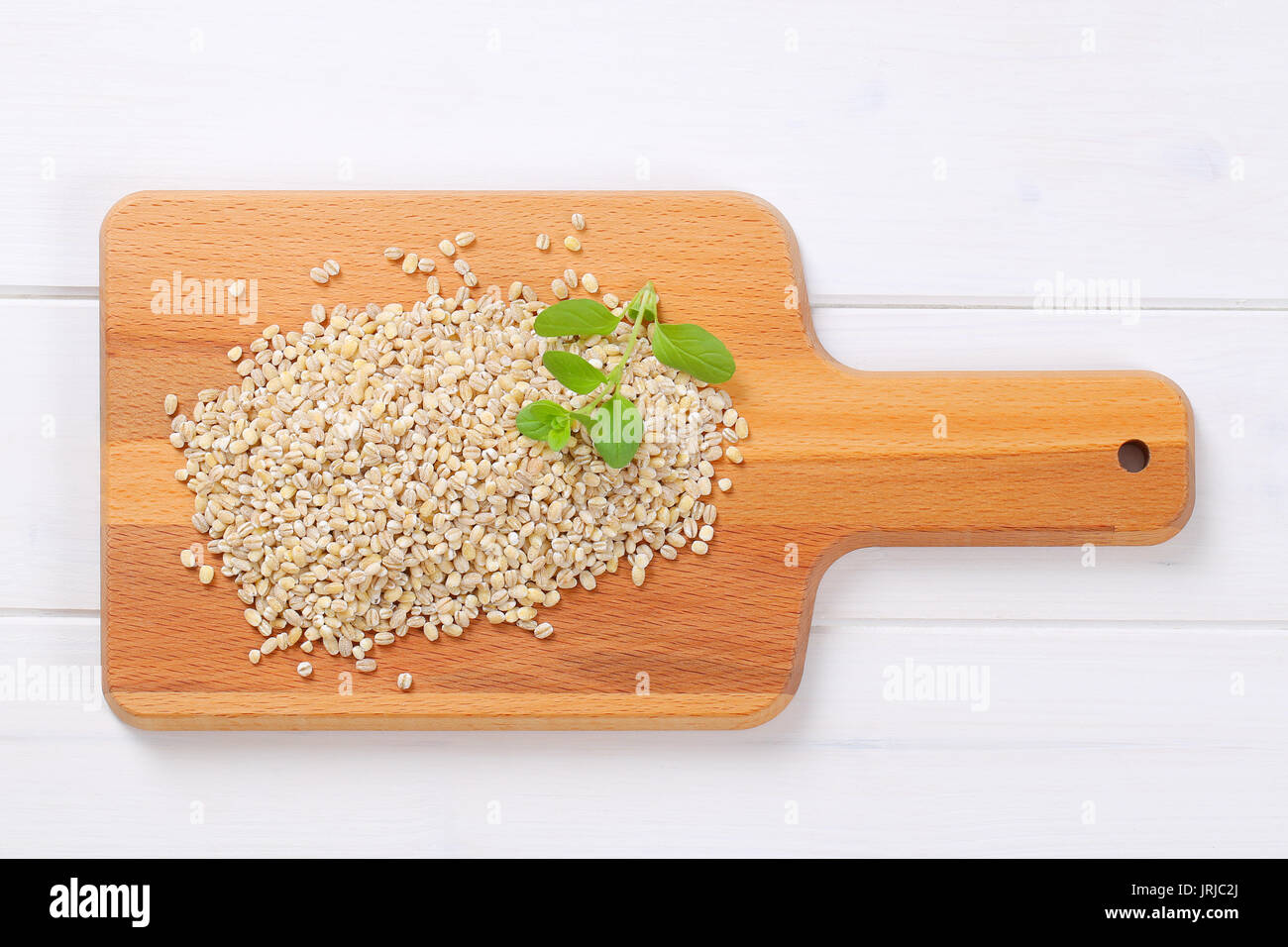 pile of pearl barley on wooden cutting board Stock Photo