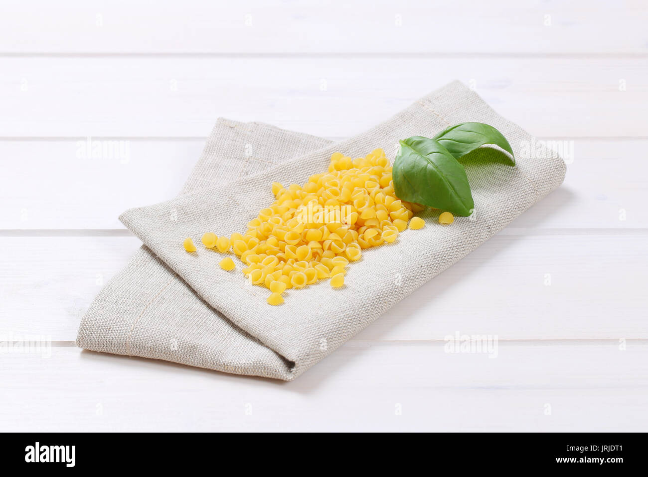 pile of small pasta shells on beige place mat Stock Photo
