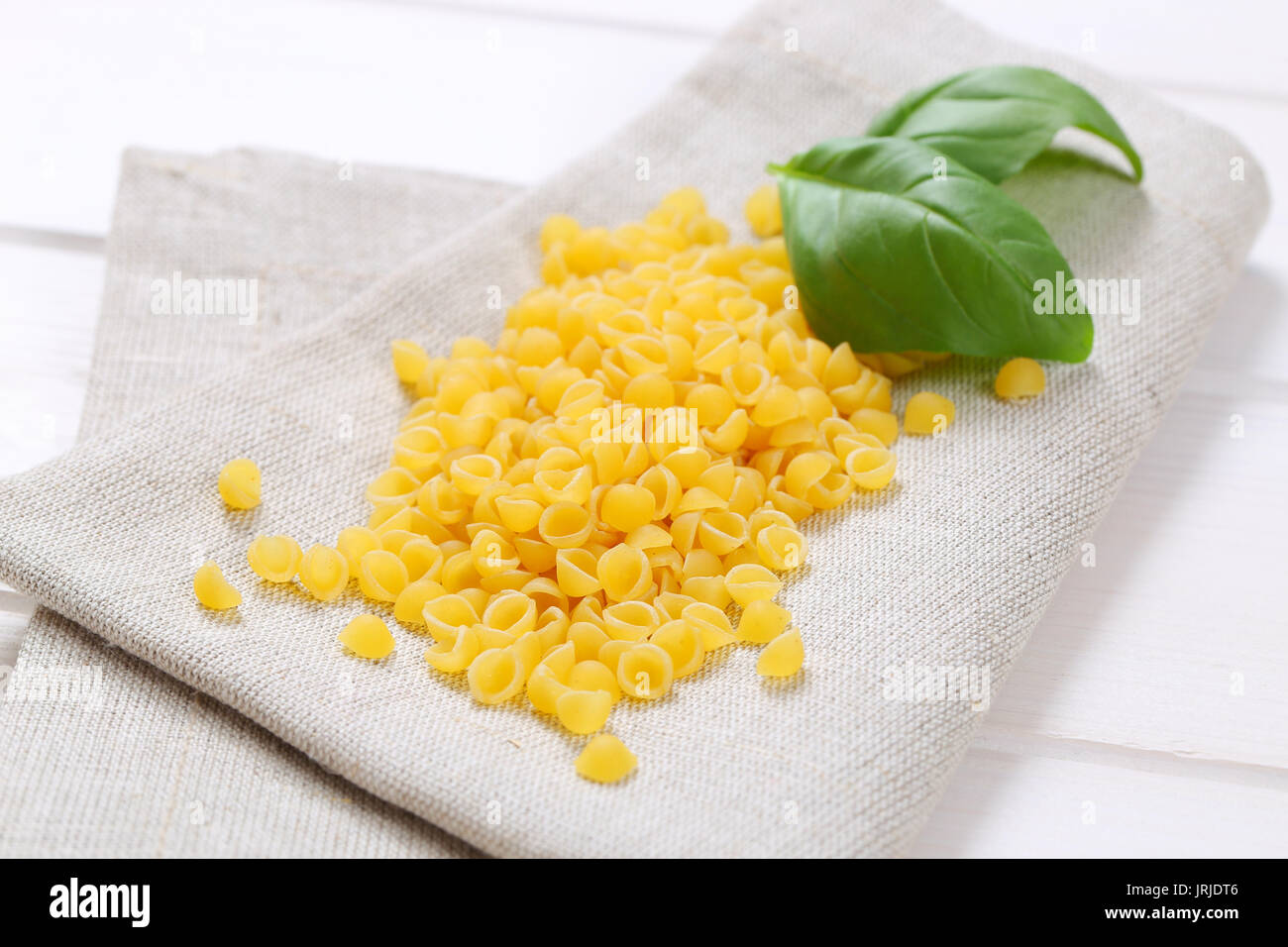 pile of small pasta shells on beige place mat - close up Stock Photo