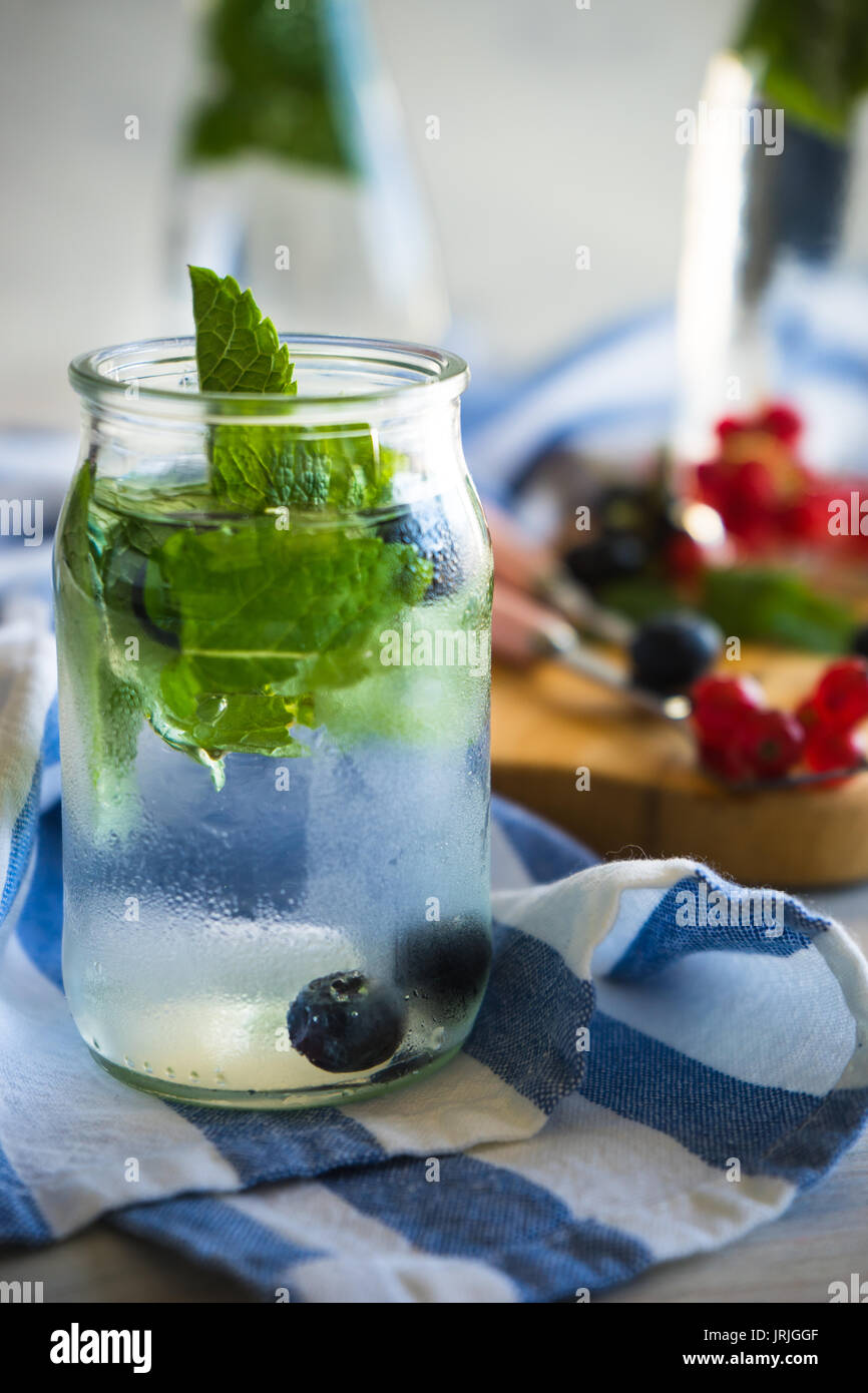 Detox summer drinks with fresh mint leaves and berries on white rustic wooden table Stock Photo