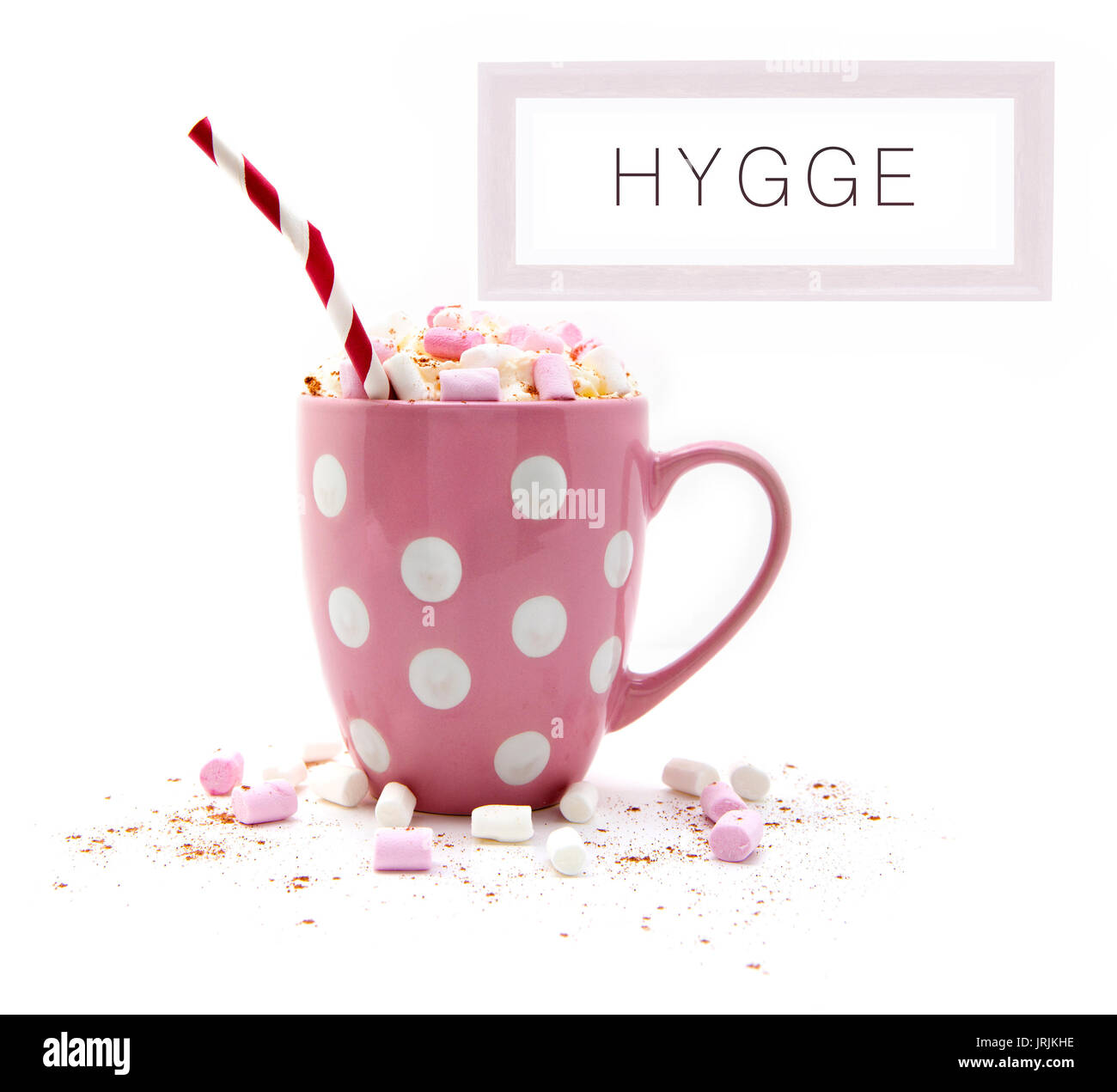 Hot Chocolate in a pink mug with marshmallows a red white striped straw and a picture of Hygge on a white background Stock Photo