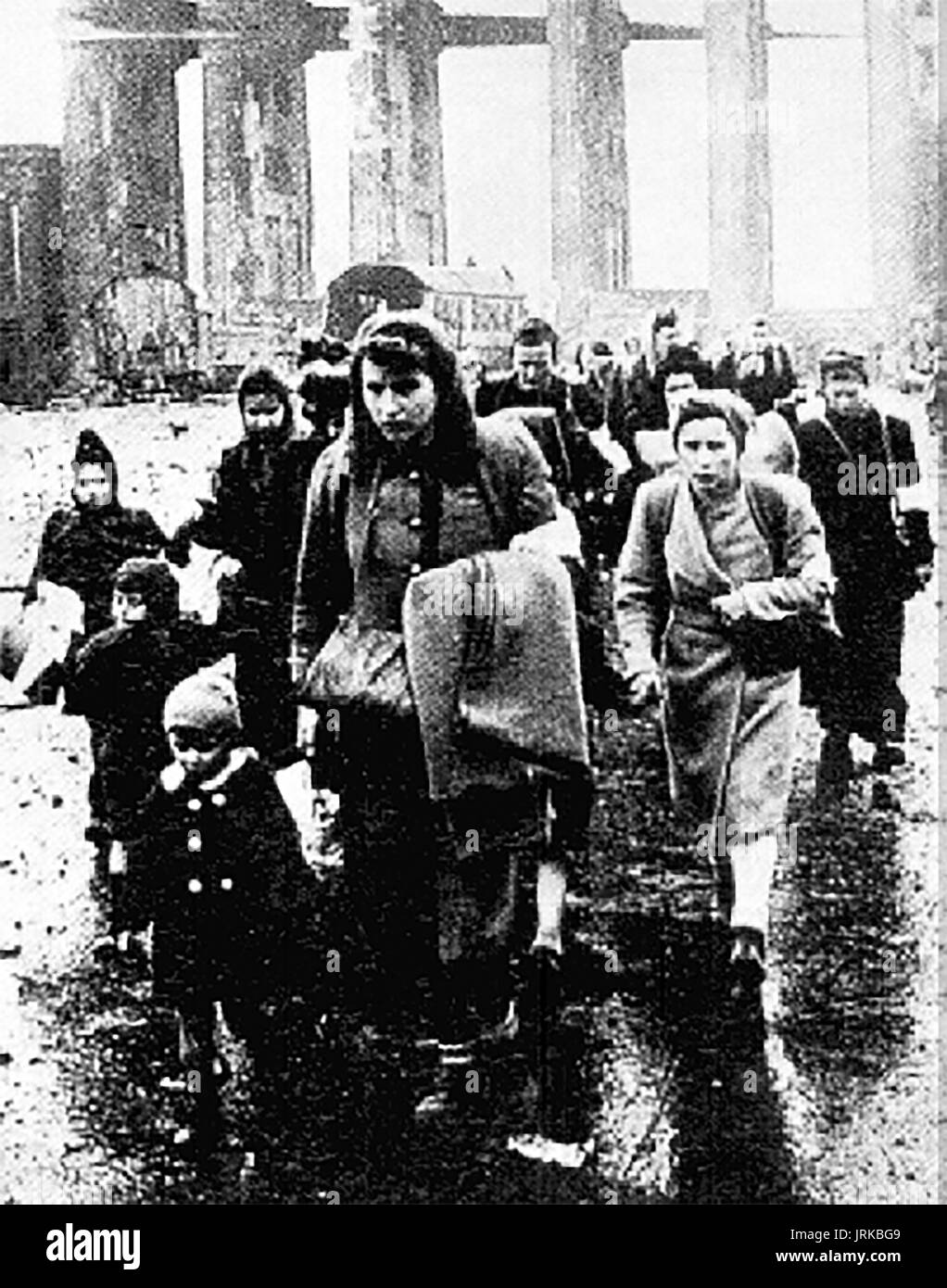 1945 following the defeat of Germany by allied forces, German refugee women and children walk through the ruins of Berlin. Stock Photo