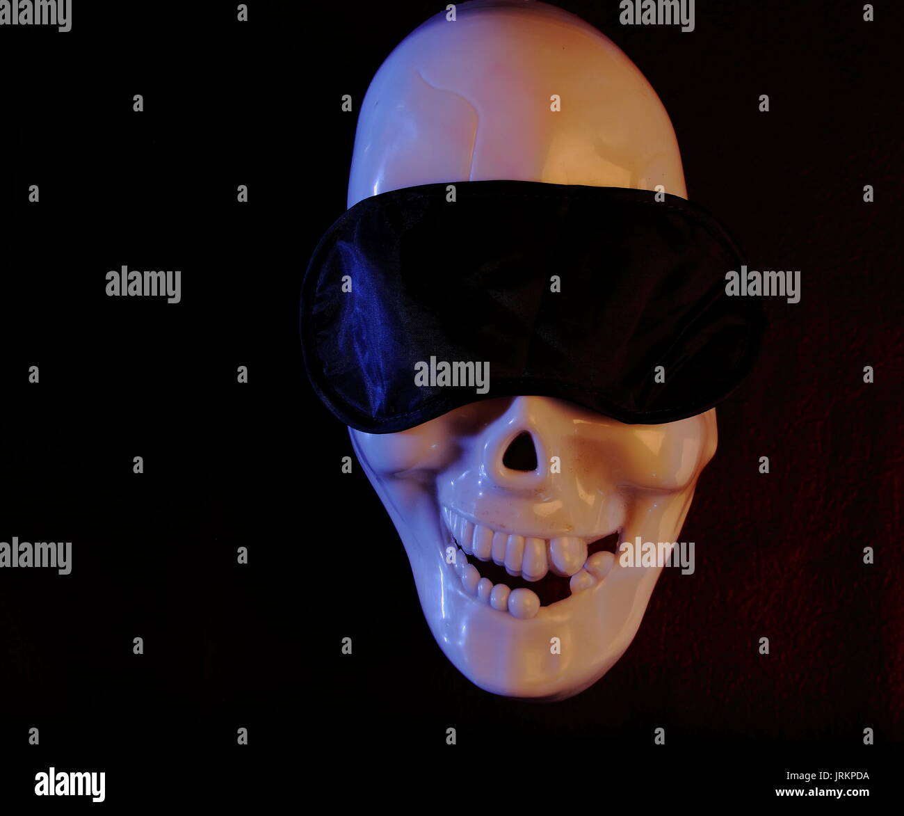 A skull mask with a sleeping eye cover on in landscape format with a dark background and copy space Stock Photo