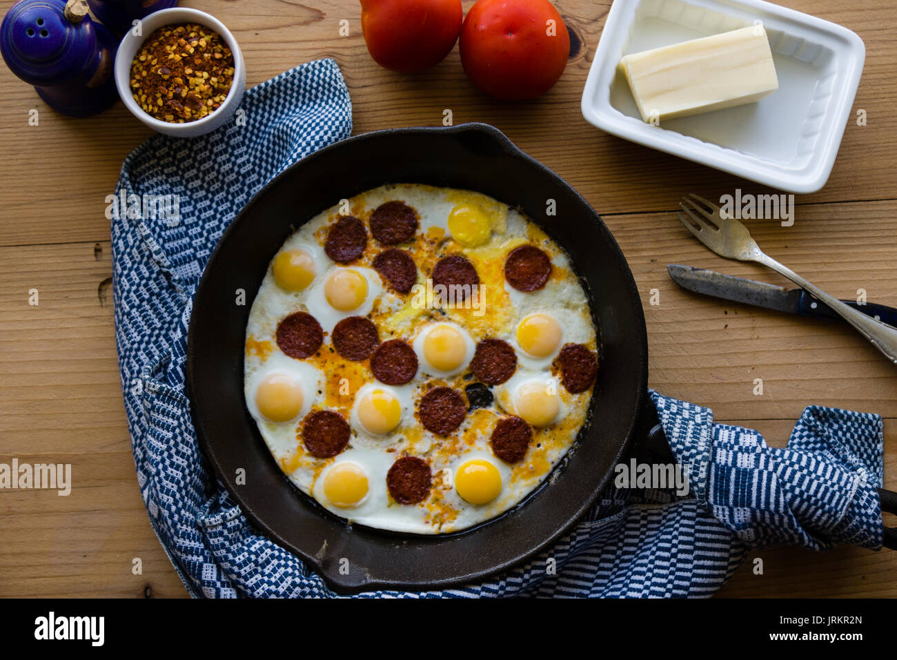 fried quail eggs with sausage in black pan Stock Photo