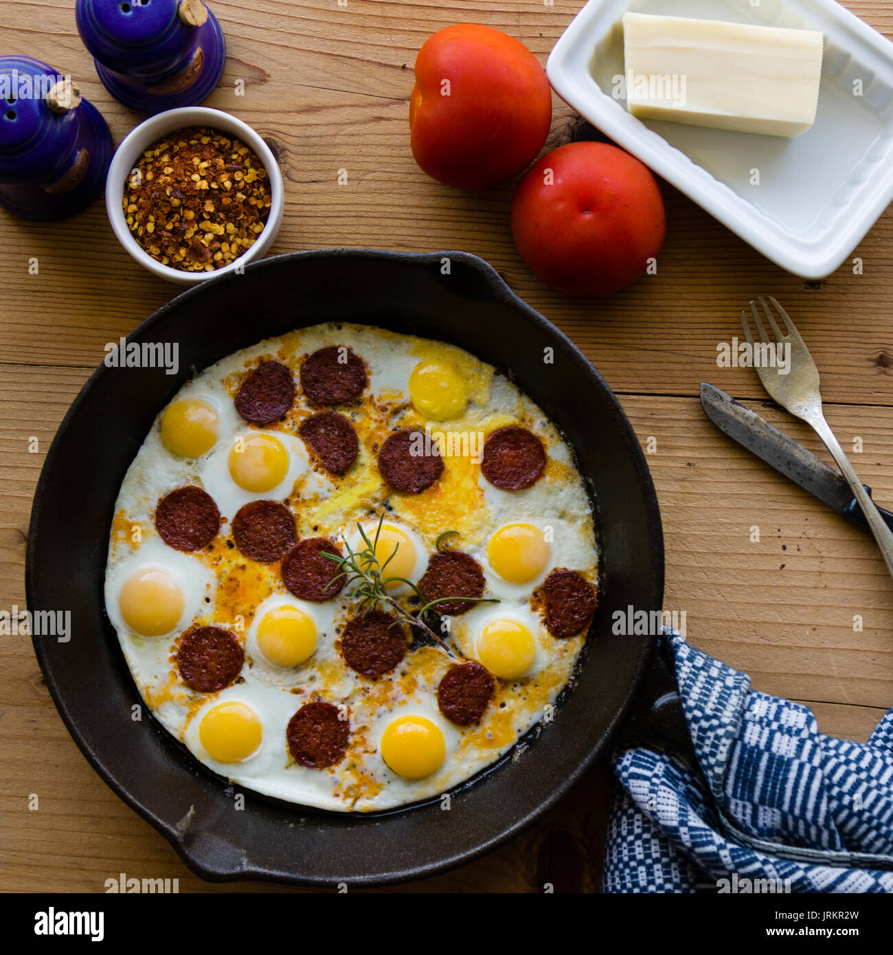 fried quail eggs with sausage in black pan Stock Photo