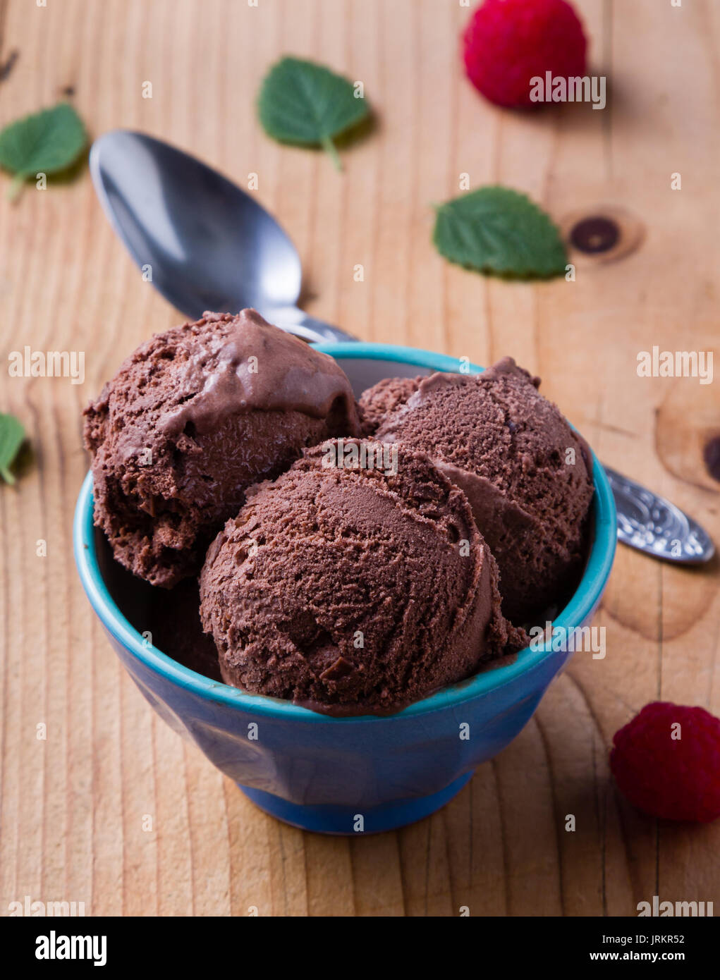 chocolate ice cream in blue bowl with raspberries Stock Photo