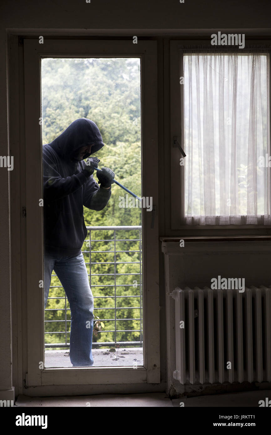 Symbol image, Apartment burglary,  burglar tries to break into an apartment, breaking up a window with tool, Stock Photo