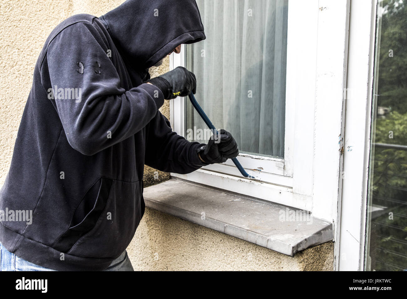 Symbol image, Apartment burglary,  burglar tries to break into an apartment, breaking up a window with tool, Stock Photo