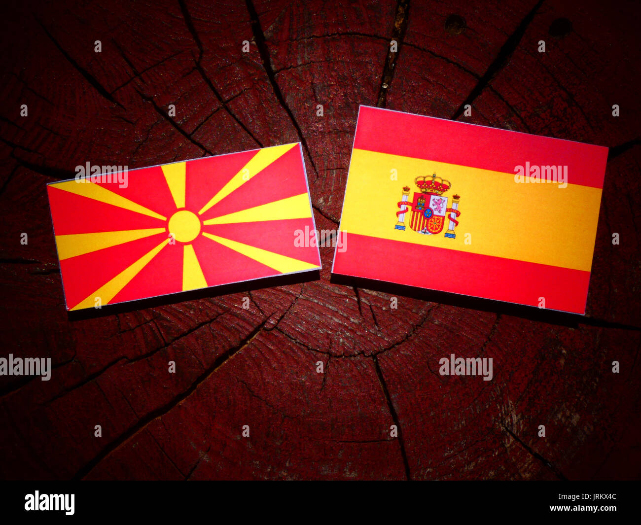 Macedonian flag with Spanish flag on a tree stump isolated Stock Photo