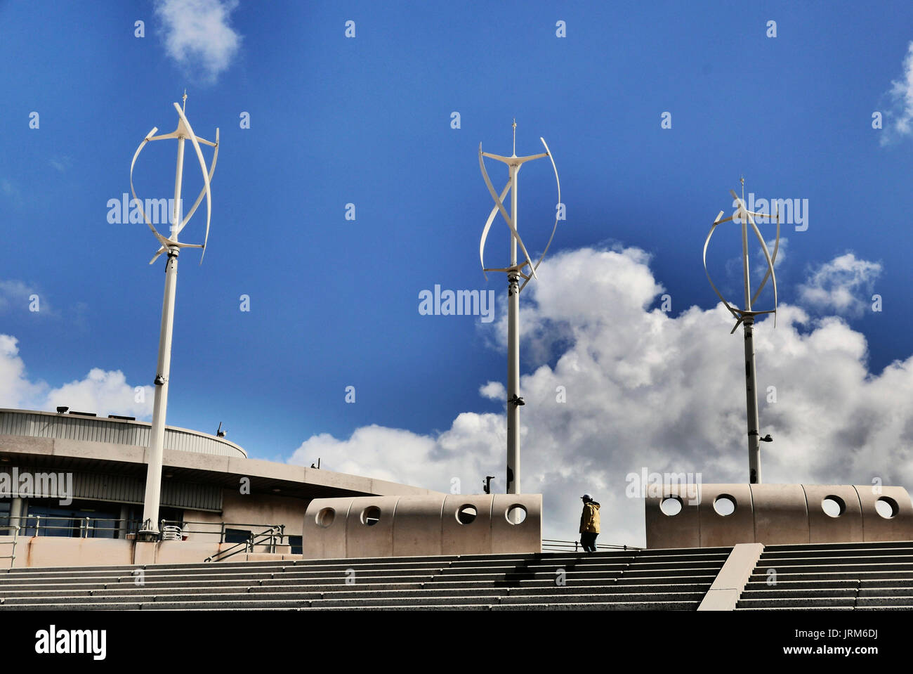 Lone man walking past three wind turbines and concrete structures on Cleveleys seawall Stock Photo