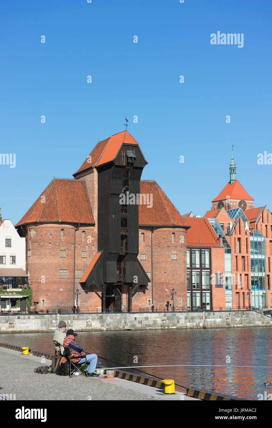 Fishermen try their luck on the canal in Gdansk's Old Town with the Gdansk medieval Port Crane in the background. Stock Photo