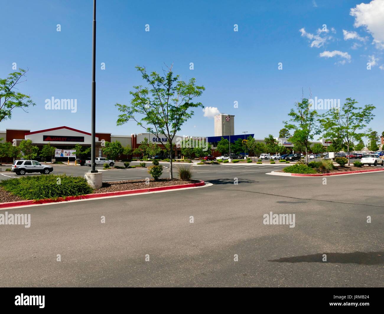 Mostly empty parking lot, strip mall, with Nestle Purina plant stack seen in the distance. Flagstaff, Arizona, USA. Stock Photo