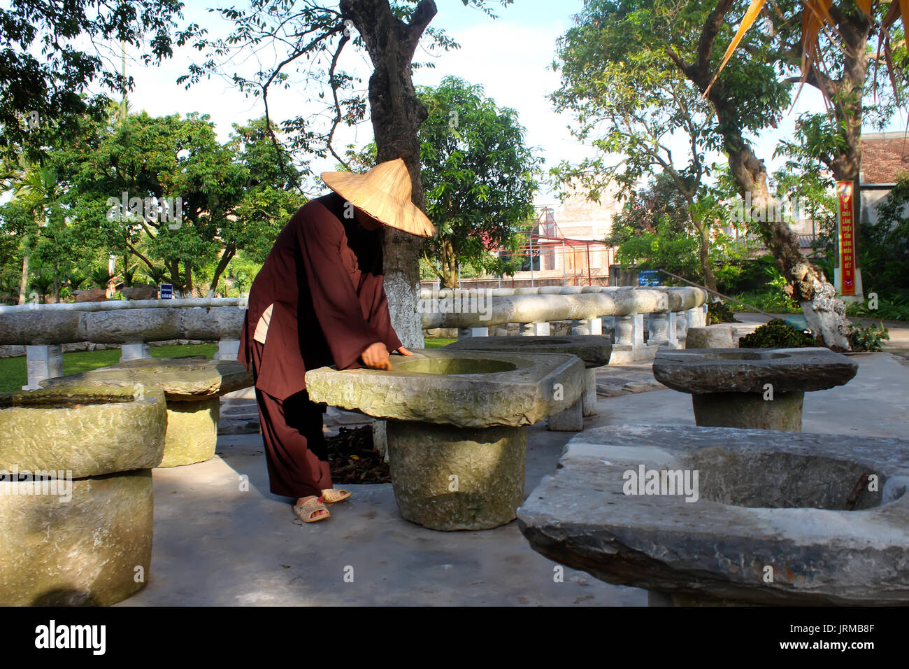 HAI DUONG, VIETNAM, September, 20: monk and old stone mortar in pagoda on September, 20, 2013 in Hai Duong, Vietnam. these are utensils people do not  Stock Photo