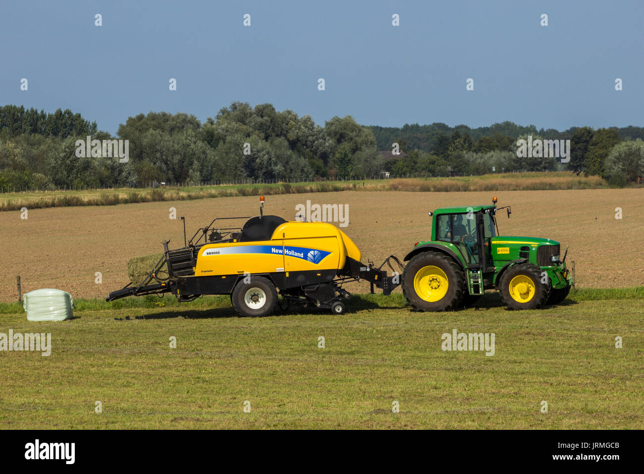ACHTERHOEK, THE NETHERLANDS - SEP 4, 2012: John Deere 6930 tractor and New Holland BB9060 CropCutter hay baler at work. Stock Photo