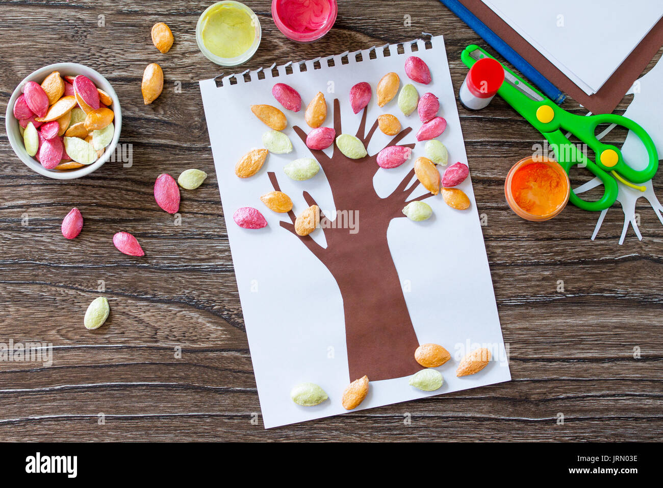Postcard autumn tree with multi-colored leaves of a pumpkin leaf on a wooden background. Children's art project, craft for children. Craft for kids. Stock Photo